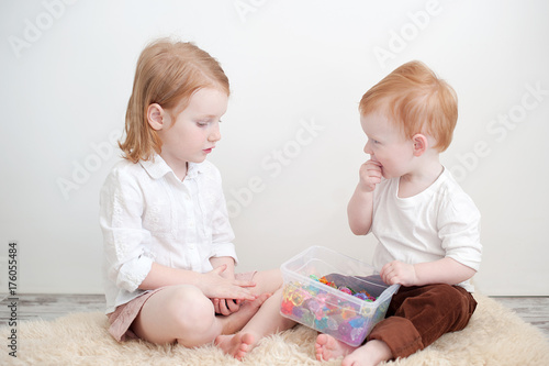 Redheads brother and sister play in the children's room