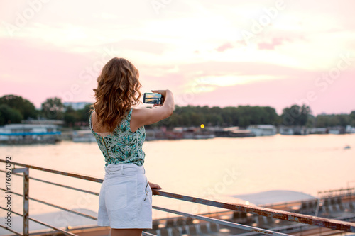 Fototapeta Naklejka Na Ścianę i Meble -  young, pretty woman on the riverside bridge with mobile phone