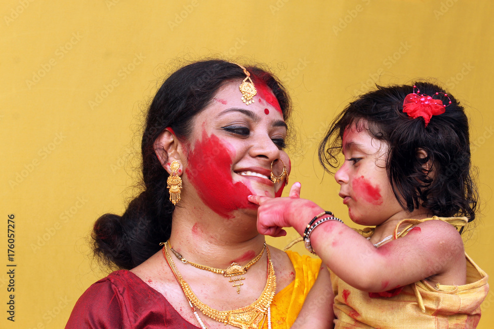 Traditional bengali woman is playing Sindur with her daughter on the