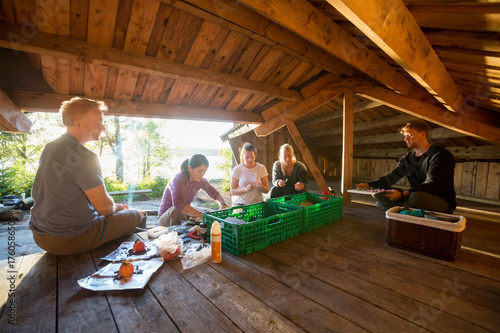 Multiethnic Friends Preparing Meal In Shed At Forest