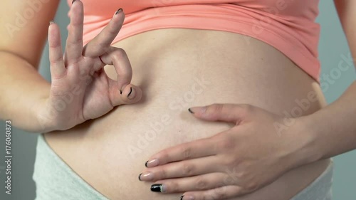 Wallpaper Mural Woman pregnant with child showing okay sign and rubbing belly, healthy pregnancy Torontodigital.ca