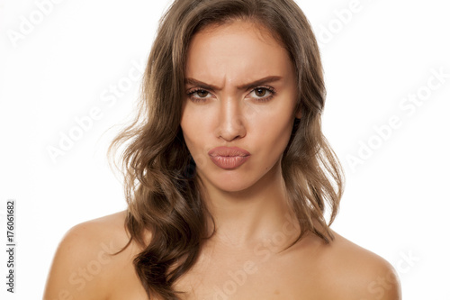Portrait of beautiful young scowling woman on white background