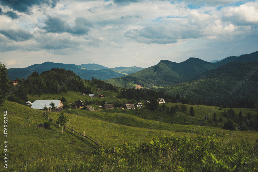 Carpathian mountains summer landscape with cloudy sky and village, natural summer travel background