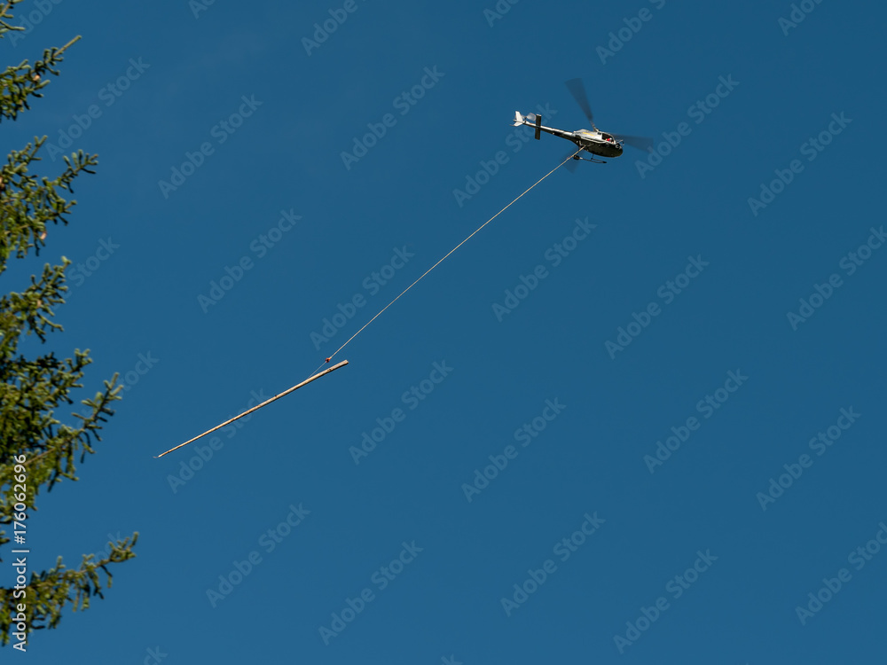 A helicopter carrying a tree trunk blue sky A helicopter carrying a tree trunk blue sky