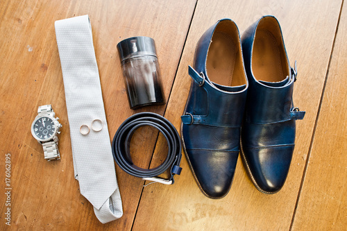 Groom's white tie, silver watch, black leather belt, perfume and a pair of wedding boots.