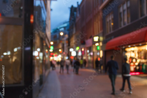 The urban landscape of the city at night with pedestrians out of focus.