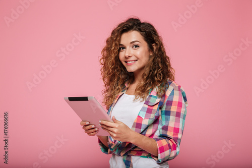 Young caucasian brunette lady using tablet computer isolated over pink
