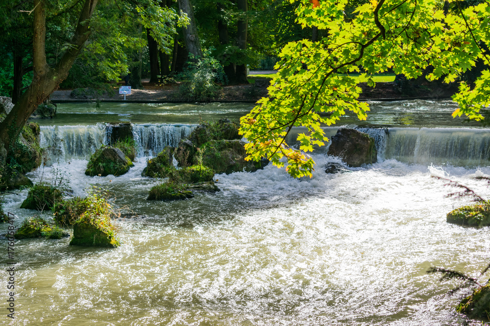 Waterfalls of the Eisbach river in English garden during autumn in