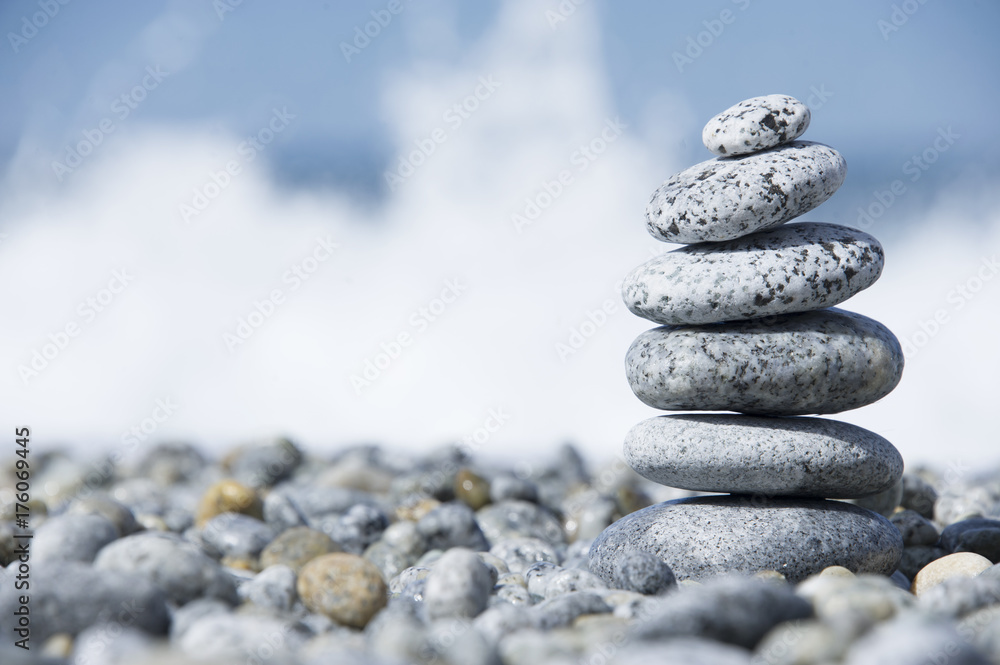 Stones pyramid on pebble beach symbolizing stability, zen, harmony, balance, concept with blur sea background Stones pyramid on pebble beach symbolizing stability, zen, harmony, balance, concept with blur sea background