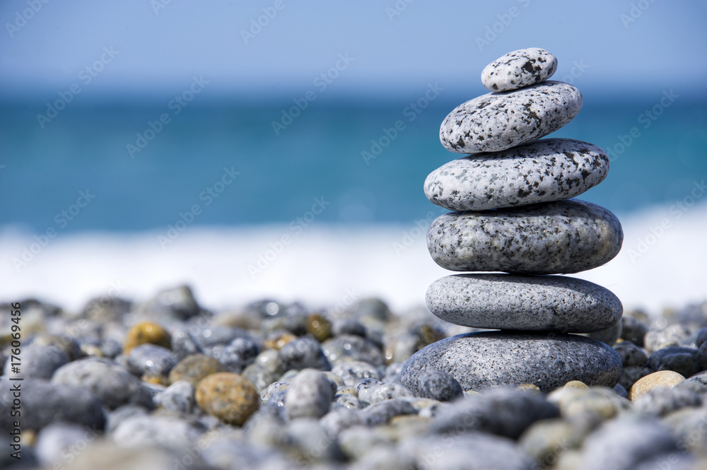 Stones pyramid on pebble beach symbolizing stability, zen, harmony, balance, concept with blur sea background Stones pyramid on pebble beach symbolizing stability, zen, harmony, balance, concept with blur sea background