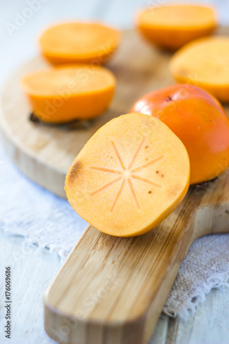 Half of persimmon fruit on wooden board.