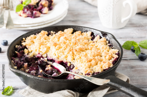 Slika na platnu Coconut crumble in cast iron pan with fresh apples and blueberry