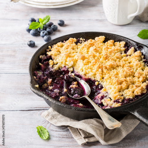 Coconut crumble in cast iron pan with fresh apples and blueberry. Healthy food concept.