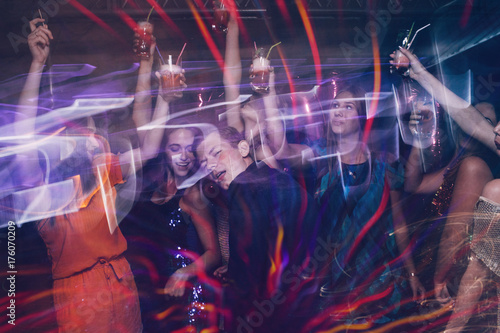 Fototapeta Naklejka Na Ścianę i Meble -  Happy company on dance floor. Joyful New Year in night club, active Christmas celebration in motion. Disco party in blurred colors, modern youth life, pickup concept