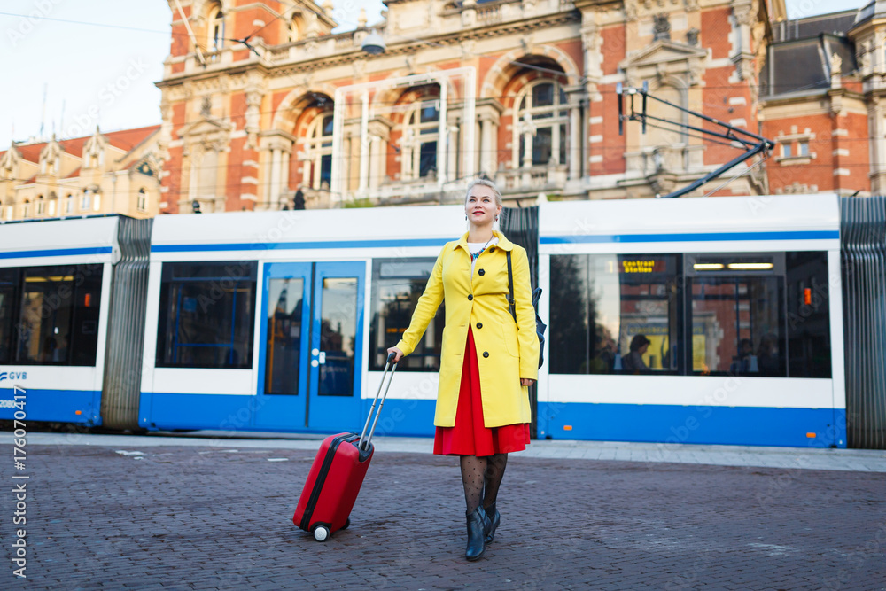 Obraz premium The woman with suitcase is walking in the street of Amsterdam city in autumn