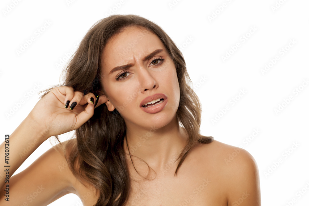 Beautiful young woman has an itch in her ear on white background Beautiful young woman has an itch in her ear on white background