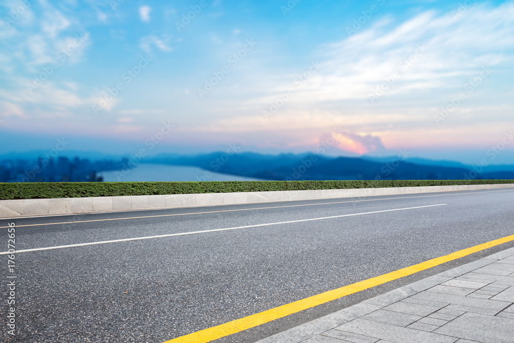 empty asphalt road with modern city near long river