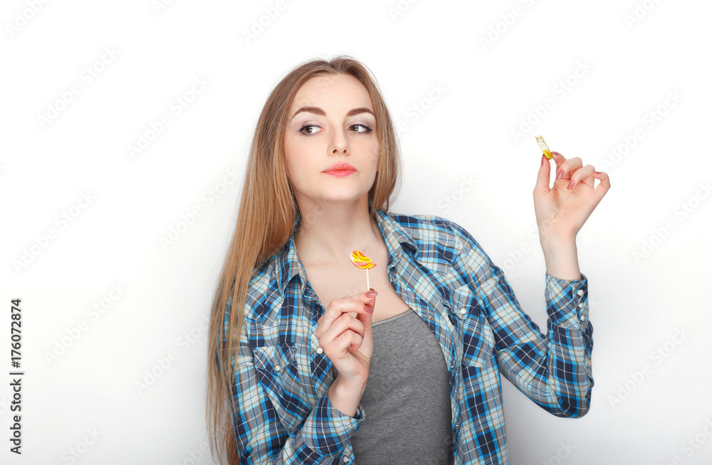 Beauty portrait of young adorable fresh looking blonde woman in blue plaid shirt posing with candy lollipop. Emotion and facial expression concept. Beauty portrait of young adorable fresh looking blonde woman in blue plaid shirt posing with candy lollipop. Emotion and facial expression concept.