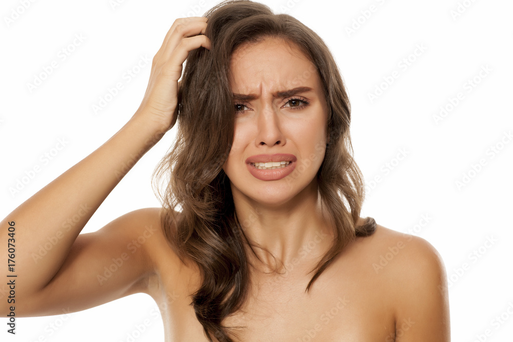 Obraz premium Beautiful young woman has an itch in her hair on white background