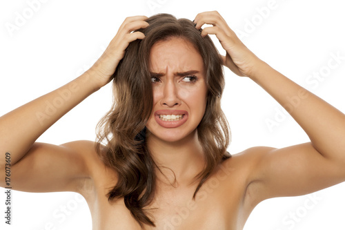 Beautiful young woman has an itch in her hair on white background