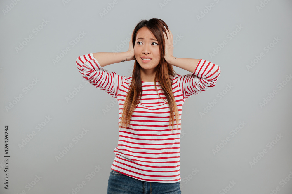 Portrait of a puzzled asian girl standing with hands Portrait of a puzzled asian girl standing with hands