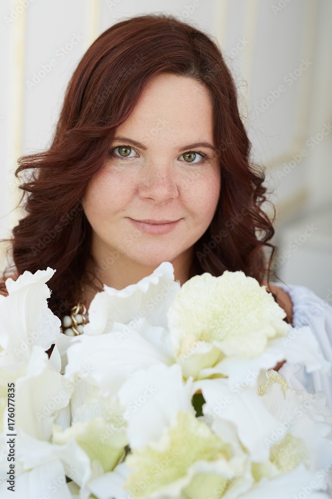 Portrait of young smilling woman holding bouquet of white flowers dressed in white dress Portrait of young smilling woman holding bouquet of white flowers dressed in white dress