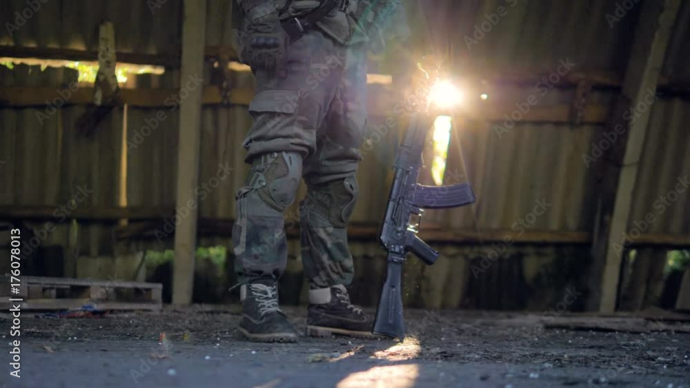 Low section of soldier with rifle standing indoors Low section of soldier with rifle standing indoors