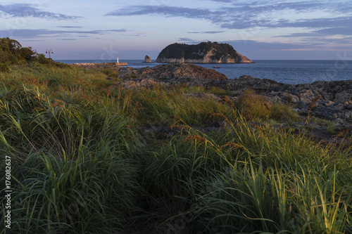 Sunset in Seogwipo with red coloured grass with view on lighthouse and Moon Island, Jeju Island, South Korea photo