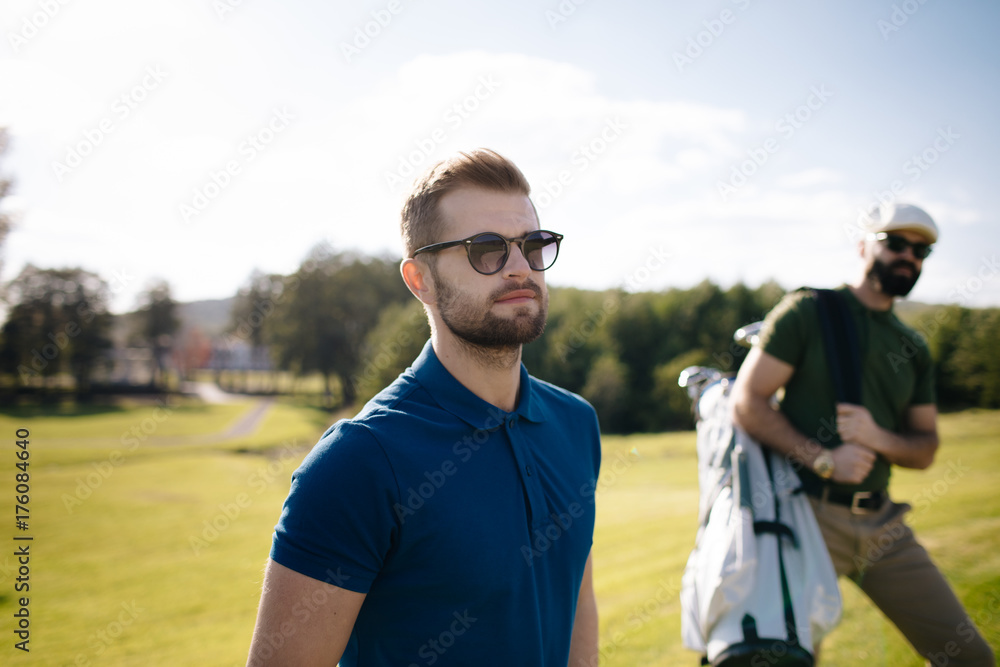 Golf player walking and carrying bag on course during summer game golfing