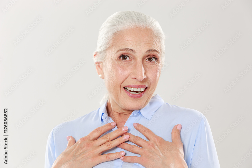 Photo of surprised old lady with hands on her chest, looking at camera Photo of surprised old lady with hands on her chest, looking at camera