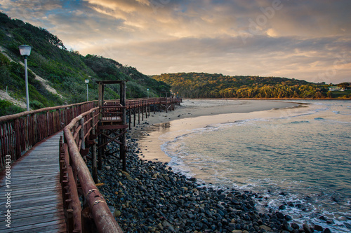 Wooden boardwalk leading to the beach under stormy skies at Gonubie, near East London, South Africa.