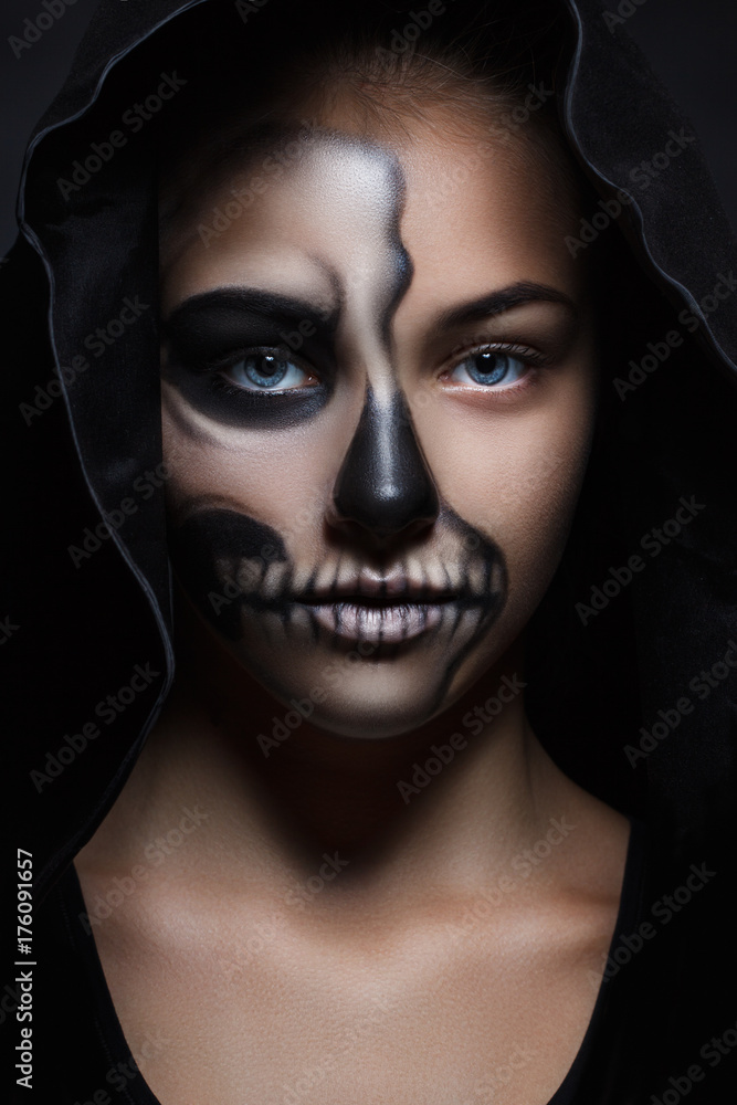 Halloween of young beautiful girl in a black hood. skeleton makeup half face Stock Photo | Adobe Stock