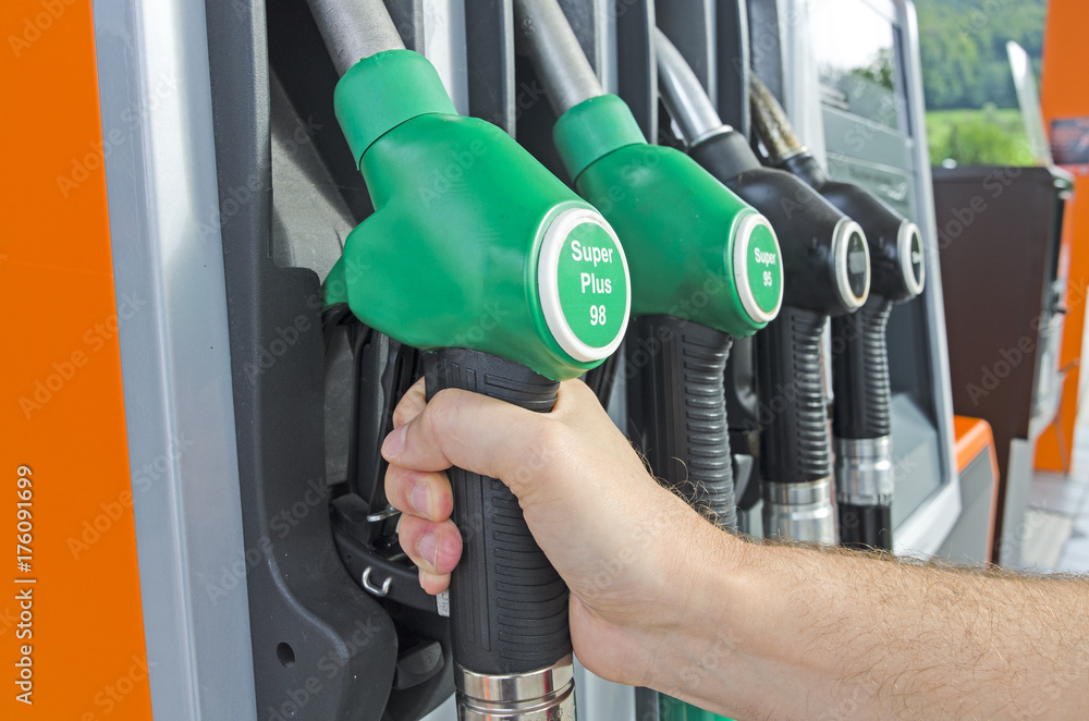 A male hand holding a gas pump nozzle at the gas station A male hand holding a gas pump nozzle at the gas station