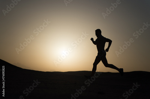 Fototapeta Naklejka Na Ścianę i Meble -  silhouette or man runner, guy running outdoor at clear sky