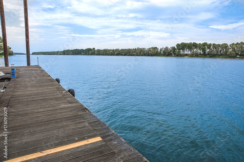 A folded spiral mooring rope with a end knot around a cleat on a wooden pier