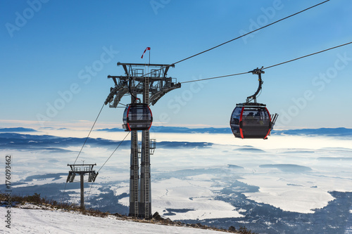 Gondola lift. Cabin of ski-lift in the ski resort in the early morning at dawn with mountain peak in the distance. Winter snowboard and skiing concept