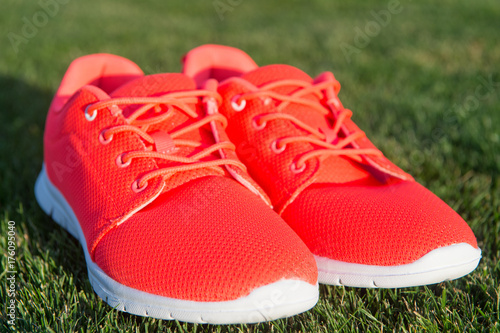 Sports shoes sneakers on fresh green grass. Sports in the open air. orange sport sneakers modern style © be free