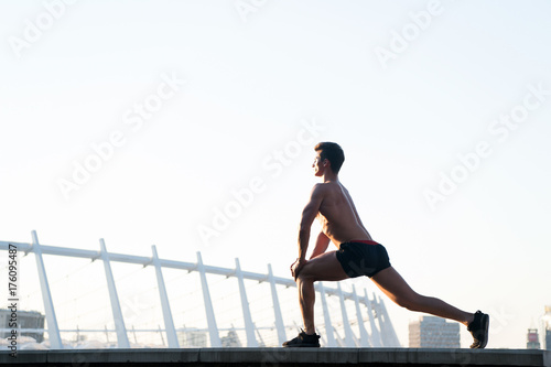 Man with muscular body doing workout on white sky