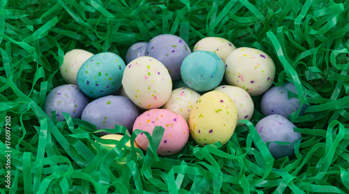 A group of speckled Easter egg malt ball candies nestled in a green plastic grass. © Bert Folsom