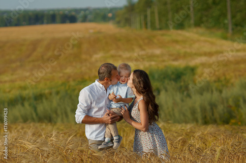 Young family walking through a wheat field © lenblr