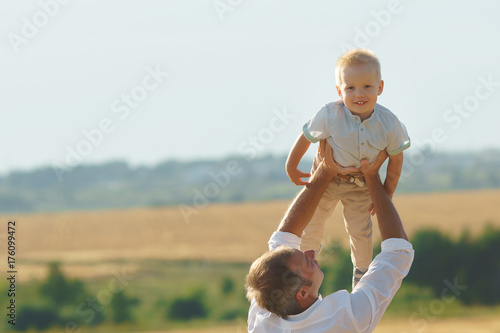 Father playing with son on summer weadow photo