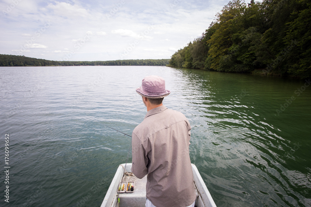 A man is fly fishing from boat on a lake. A man is fly fishing from boat on a lake.