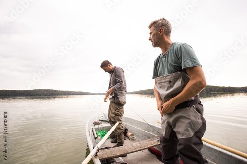 Two mature men are putting on waders before fly fishing from a lake. photo