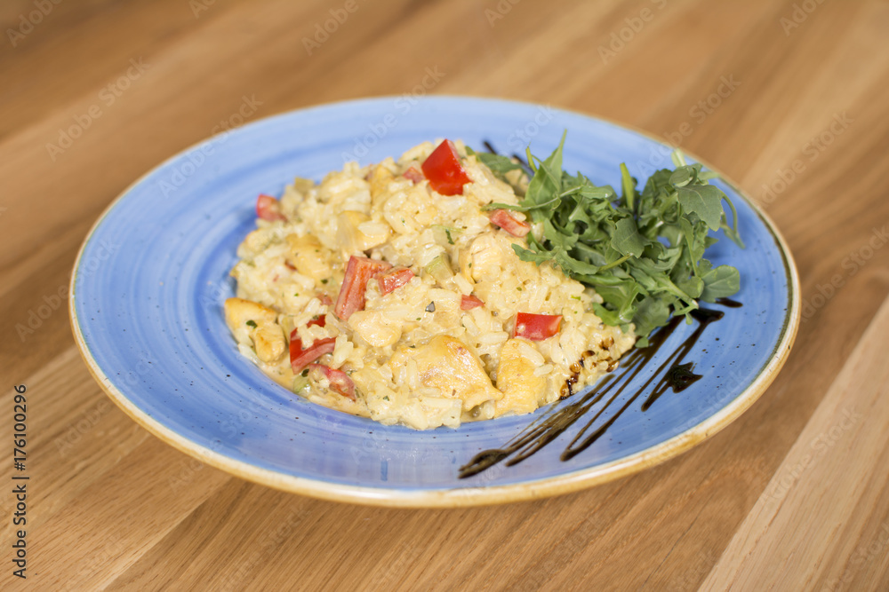 A plate of rice with vegetables. Appetizing healthy rice with vegetables in white plate on a wooden background.