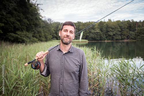 Caucasian fly fisher with his fishing rod at a lake. photo