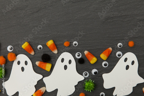 Halloween background with ghosts and candy corn on a slate background