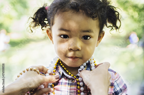 Little Asian girl, putting on beads necklass photo