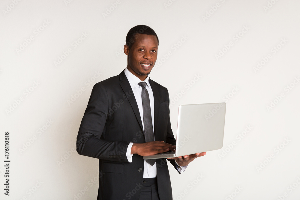 Black male happy manager in suit, tie standing, holding laptop at hands. Portrait Black male happy manager in suit, tie standing, holding laptop at hands. Portrait