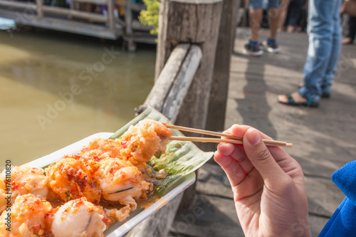 Close up holding mini Fried Mussels by chopsticks,Floating market at Ayutthaya photo