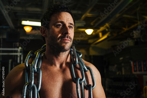 A shirtless muscular male draped in heavy chains. photo